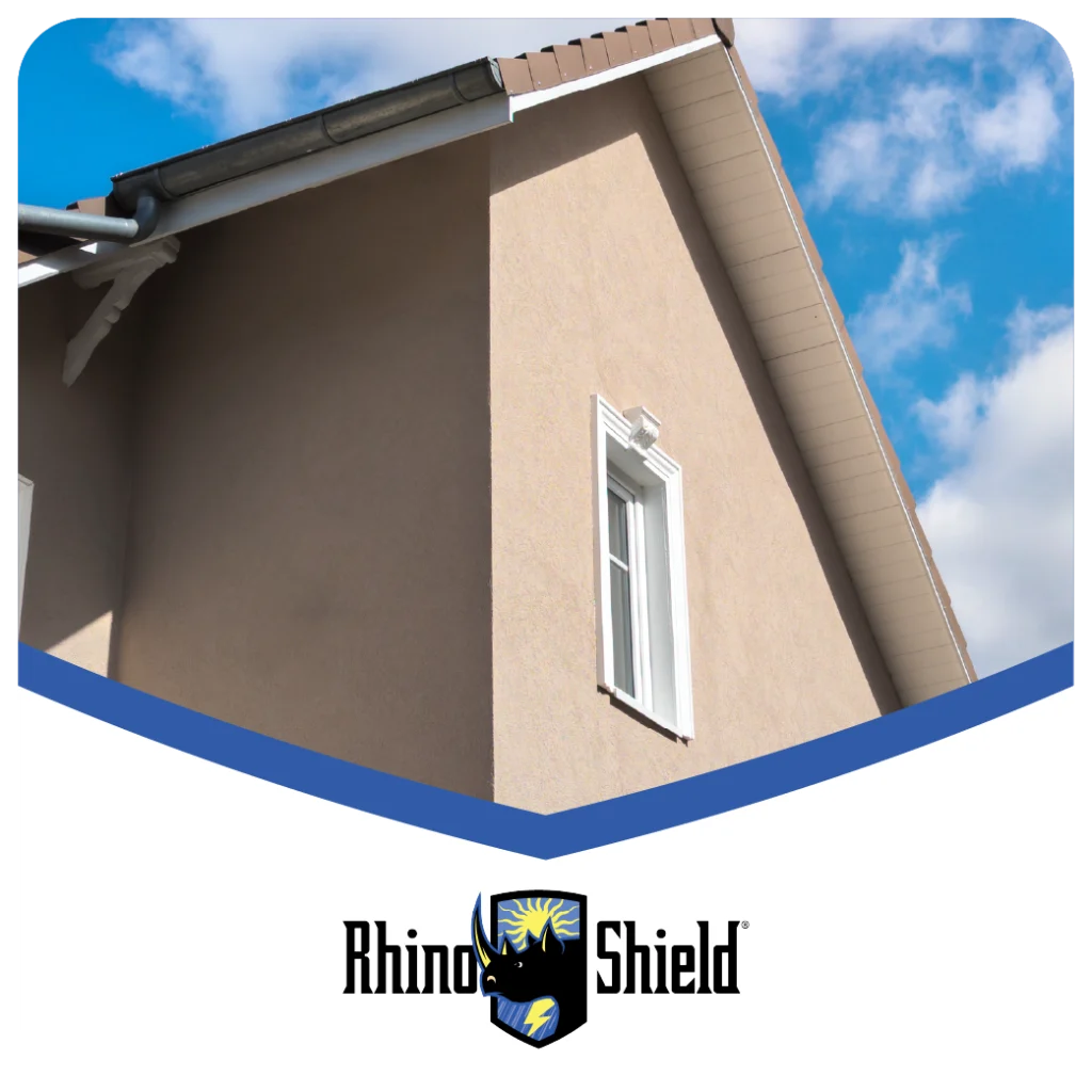 Beige stucco house exterior with Rhino Shield logo at the bottom